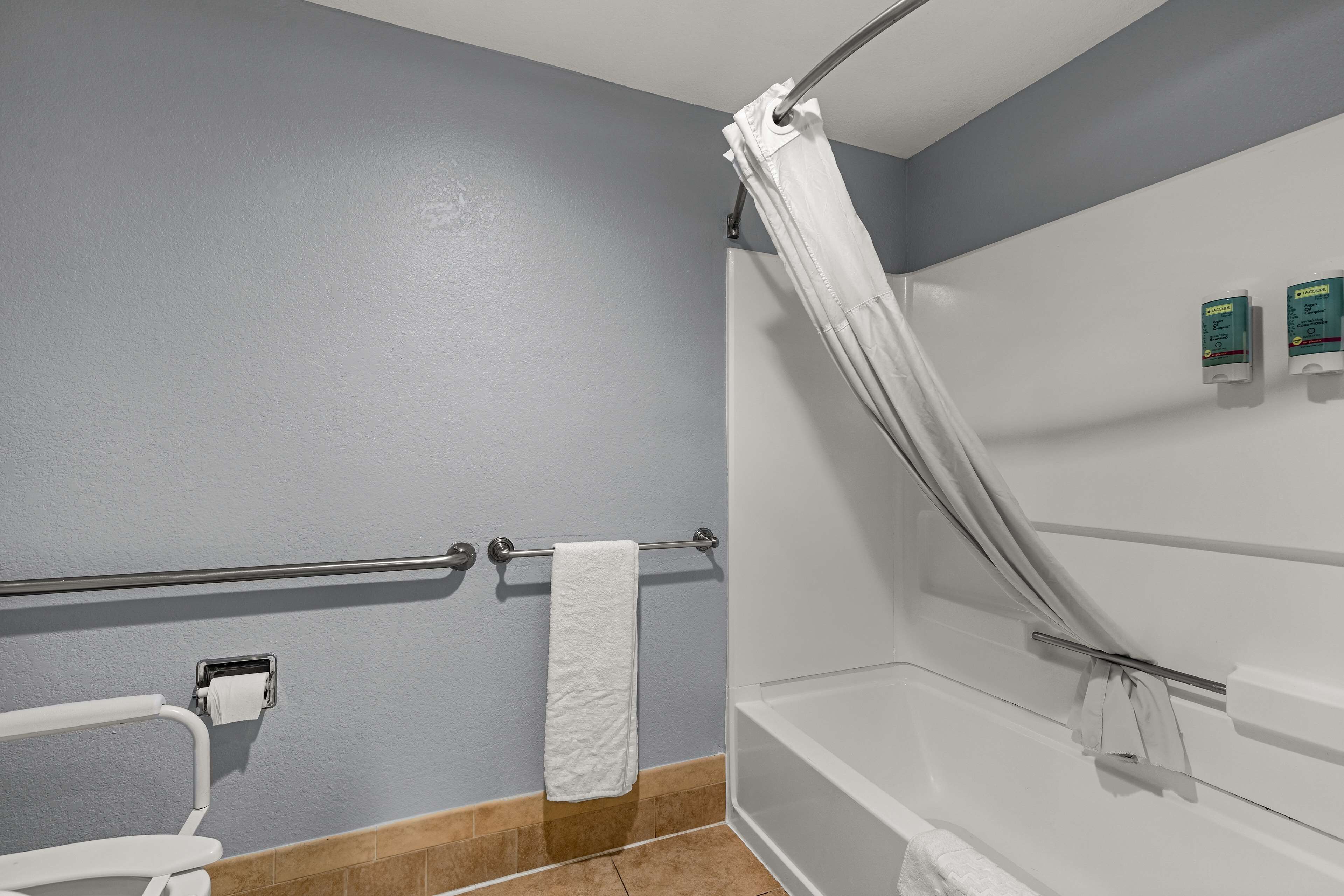 A bathroom with a shower, a towel rack, a toilet, and a hand dryer.