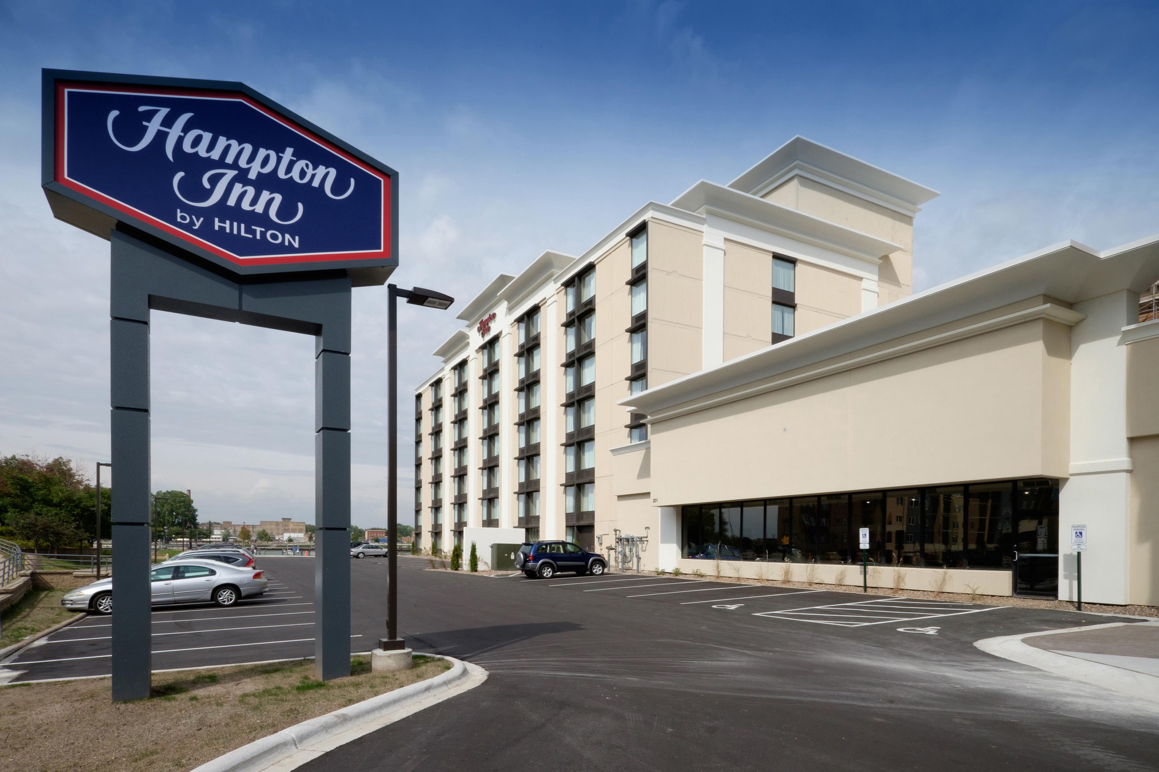 A Hampton Inn by Hilton sign and a hotel building with a modern design.