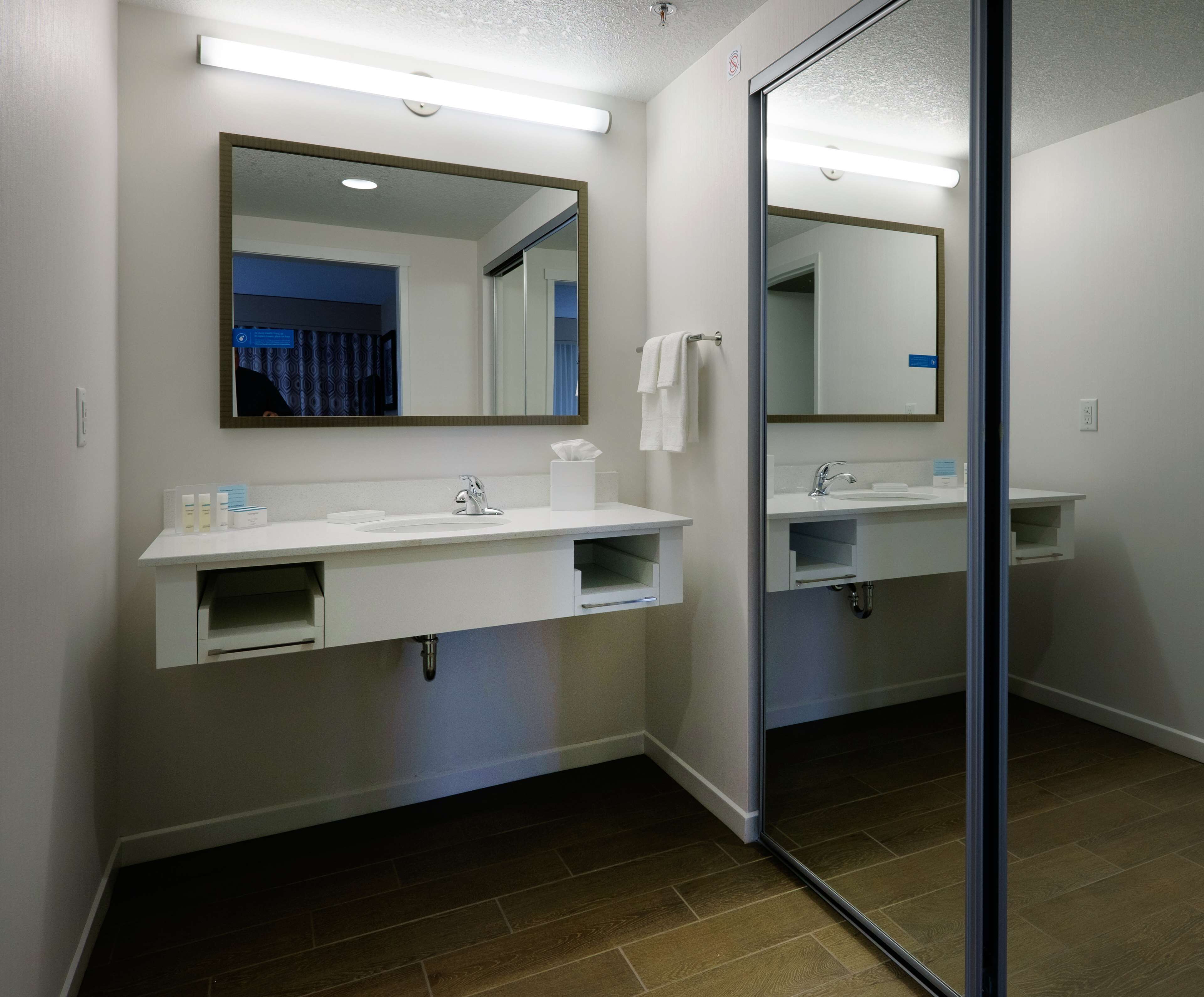 A modern bathroom with a white vanity, a large mirror, and a separate sink.