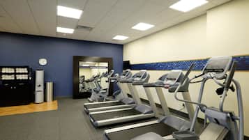 A gym with treadmills, a clock, and a trash can.