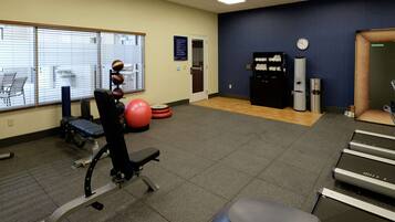 A gym with exercise equipment, a treadmill, and a wall clock.