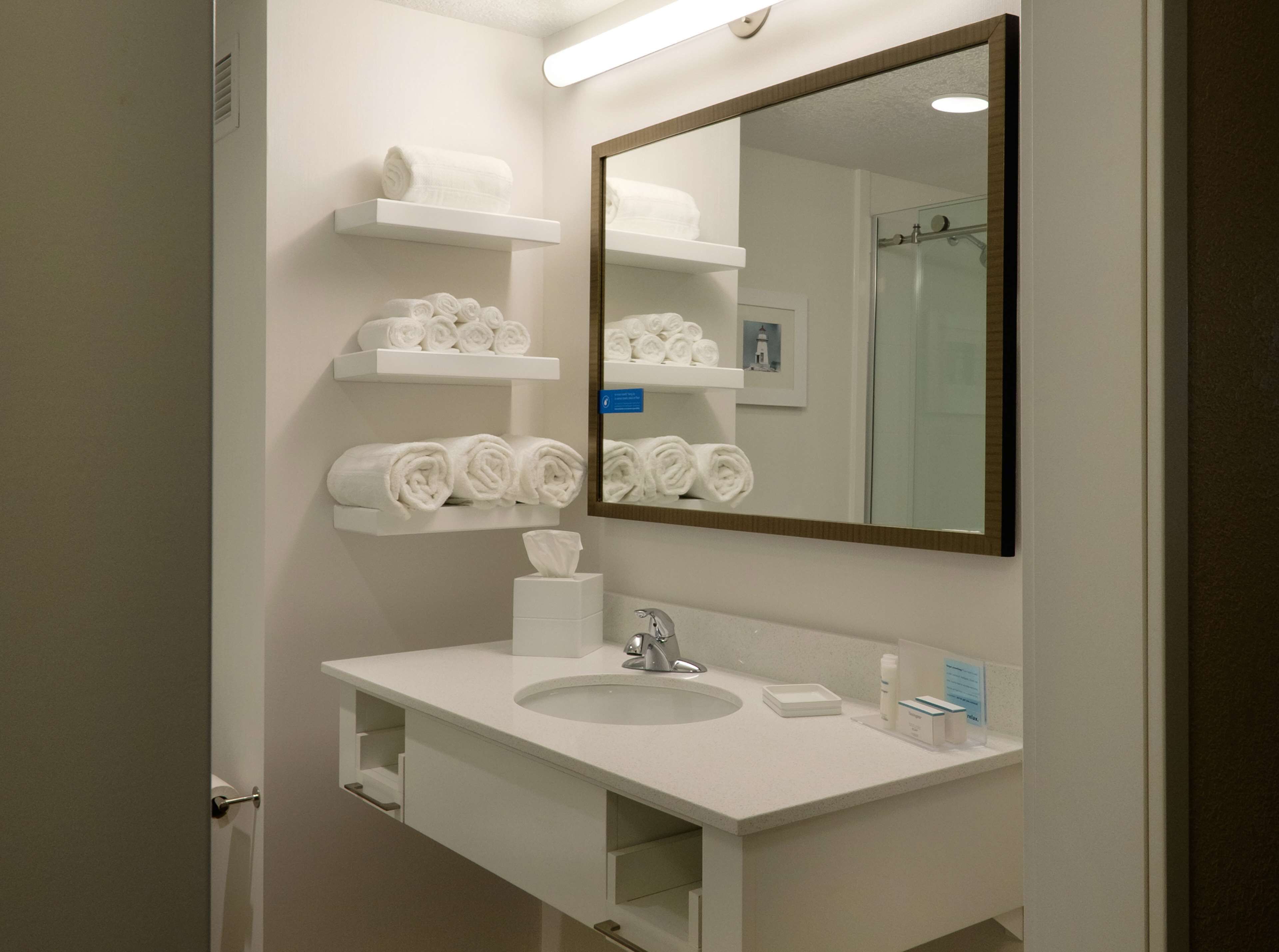 A modern bathroom with a white sink, mirror, and towel racks.