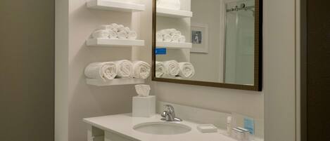 A modern bathroom with a white sink, mirror, and towel racks.