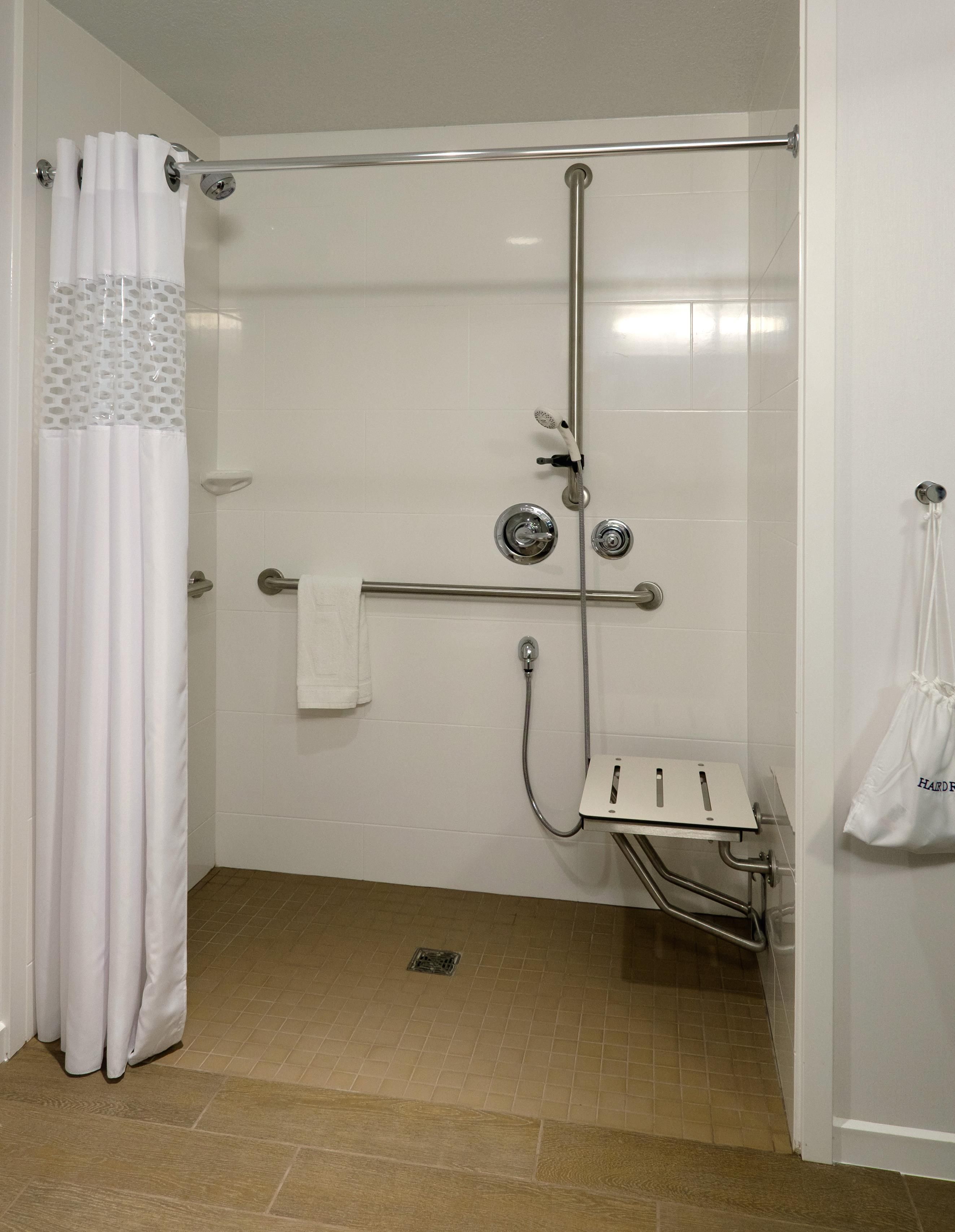 A shower area with a grab bar, a towel rack, and a showerhead.