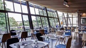 Un restaurante con diseño interior moderno, ventanas amplias y vistas al exterior.