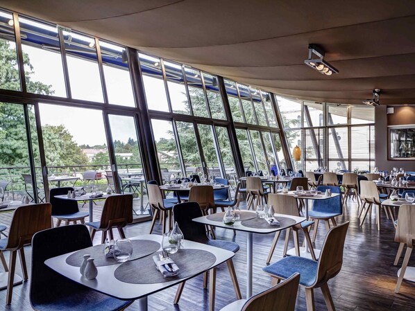 Ein Restaurant mit modernem Interieur, großen Fenstern und Blick ins Freie.