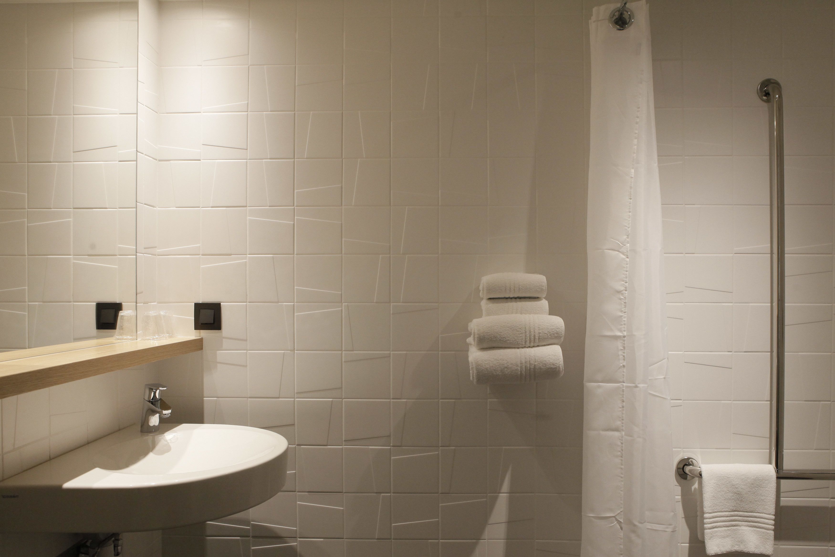Une salle de bain équipée d’un lavabo, d’un miroir et d’un espace douche.