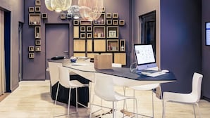 Un espacio de oficina moderno con una mesa de vidrio, sillas blancas, un ordenador de escritorio e iluminación decorativa.