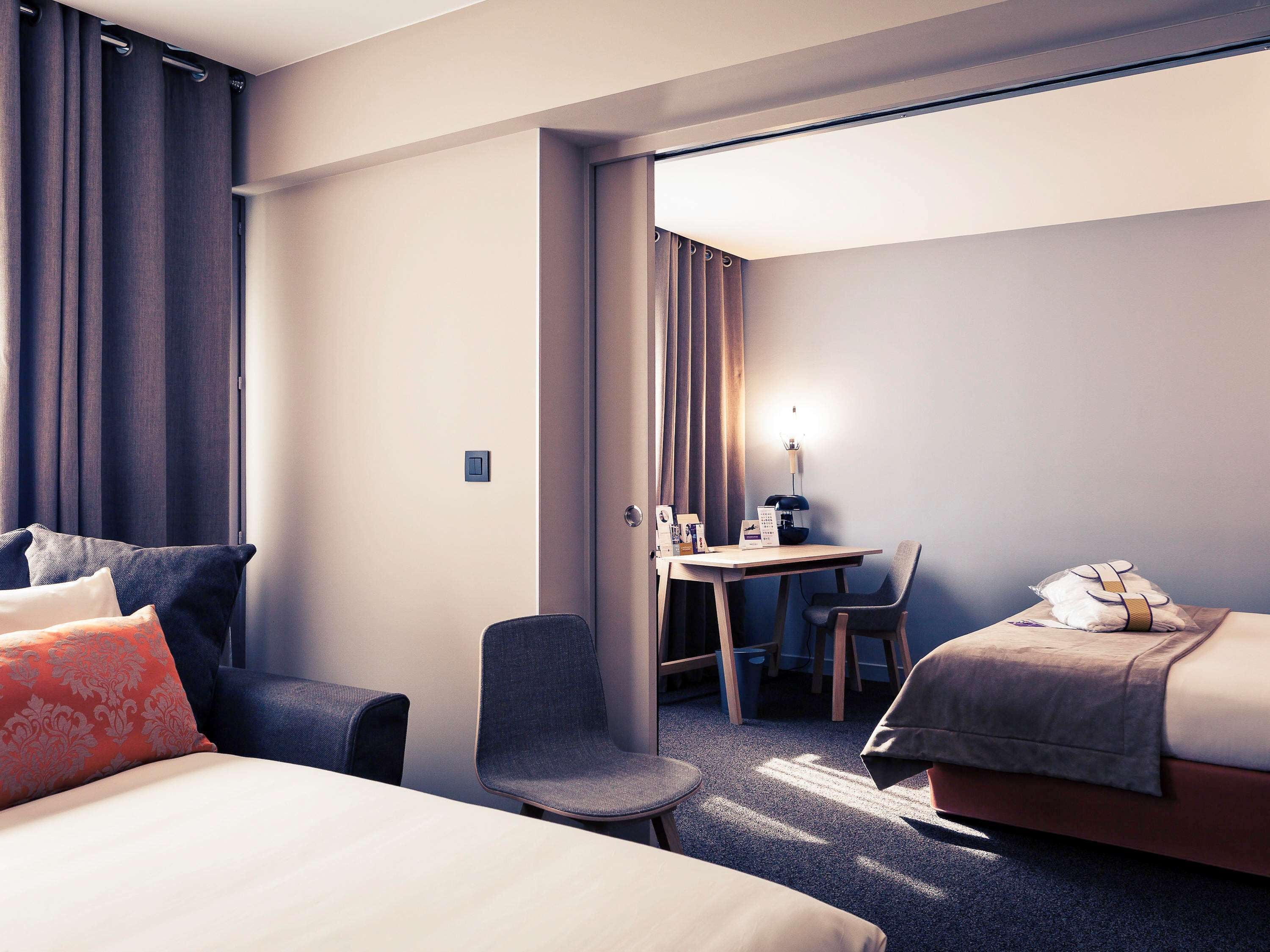 Una habitación de hotel con una cama, un escritorio con una silla, una mesita y un sofá.