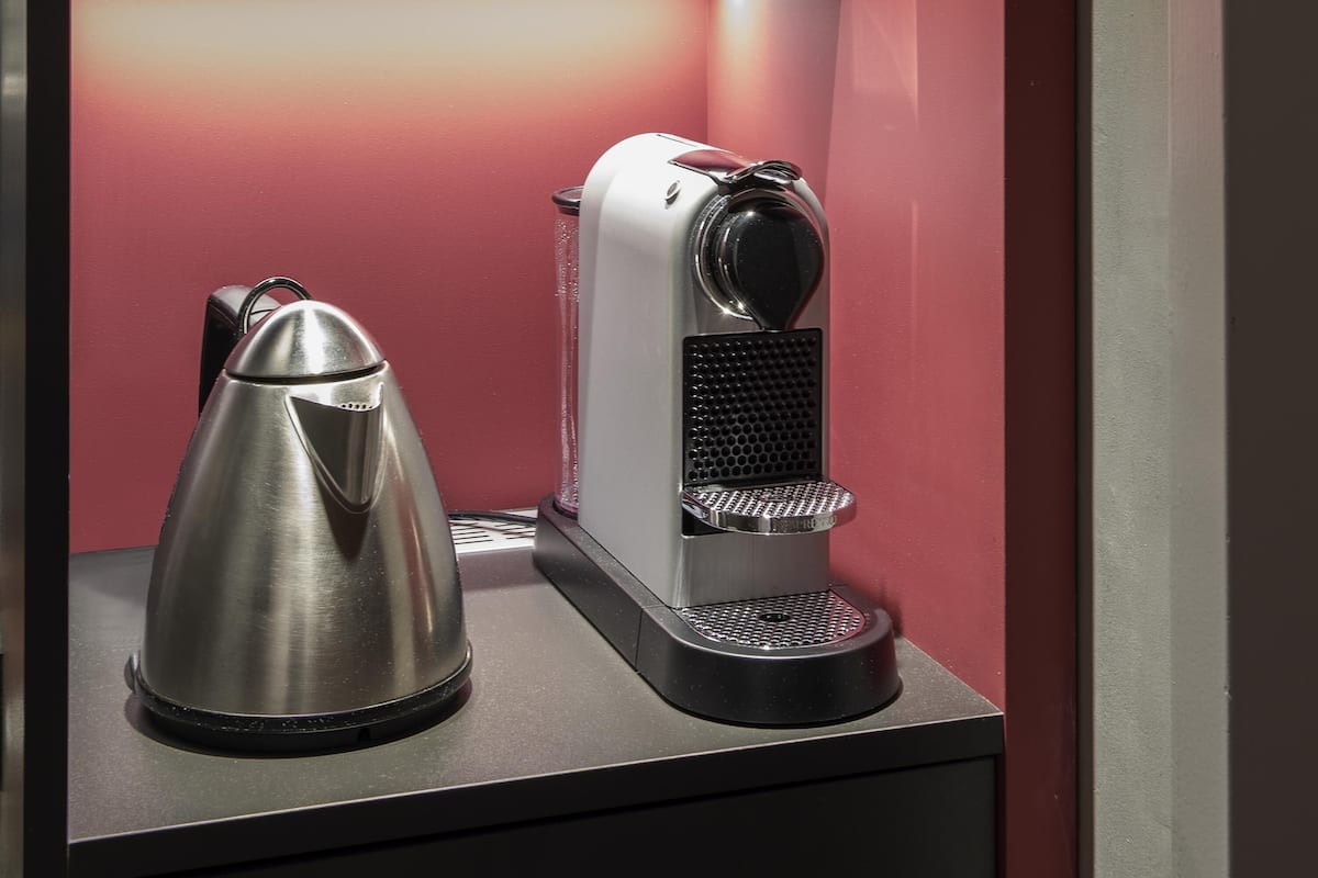 Une machine à café et une bouilloire sont posées sur un plan de travail.