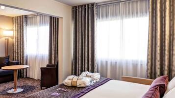 Quarto de hotel com cama, escrivaninha, cadeira e sofá.
