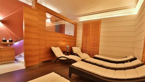 A spa room with a curved seating area, wooden panel walls, and a small table with a candle. - Best Western Hotel Genio (Turin)