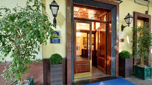 The entrance of the Best Western Genio hotel with a blue doormat, a potted plant, and a sign indicating the hotel's name. - Best Western Hotel Genio (Turin)
