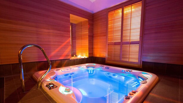 A hot tub with a metallic faucet, surrounded by wooden walls and a tiled floor. - Best Western Hotel Genio (Turin)