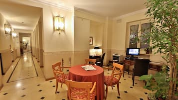 Un comedor de hotel con una mesa redonda, sillas, un televisor y una planta en maceta.