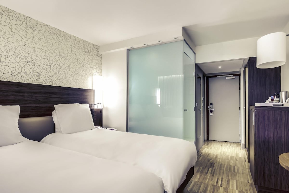 Ein Hotelzimmer mit einem großen Bett, einem Schreibtisch, einem Spiegel und einer Tür zu einem Badezimmer.