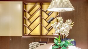 A modern interior with a wooden bookshelf, a dining table, and a potted orchid. - Mercure Paris Arc de Triomphe Etoile (Paris)