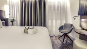 A modern hotel room with a large bed, a chair, a desk, and a TV. - Mercure Paris Arc de Triomphe Etoile (Paris)