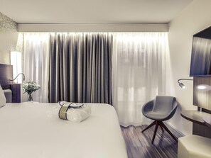 A modern hotel room with a large bed, a chair, a desk, and a TV. - Mercure Paris Arc de Triomphe Etoile (Paris)