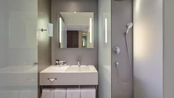 A modern bathroom with a large mirror, a dual sink vanity, and a walk-in shower.
