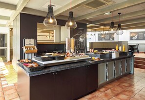 A breakfast bar with a variety of food items, including pastries and condiments.