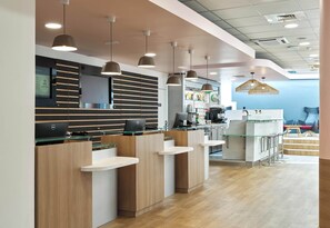 A modern reception area with a counter, seating, and a coffee machine.