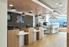 Un área de recepción moderna con mostrador, asientos y una máquina de café.