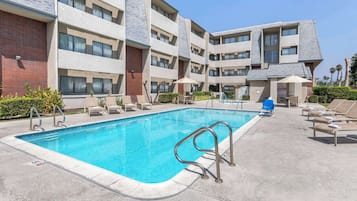 Un hotel con piscina, mobiliario exterior y fachada de ladrillo.