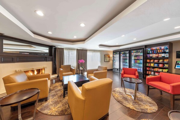 A hotel lobby with seating areas, a fireplace, a self-service beverage station, and a large mirror. - Best Western Plus West Covina Inn (West Covina)