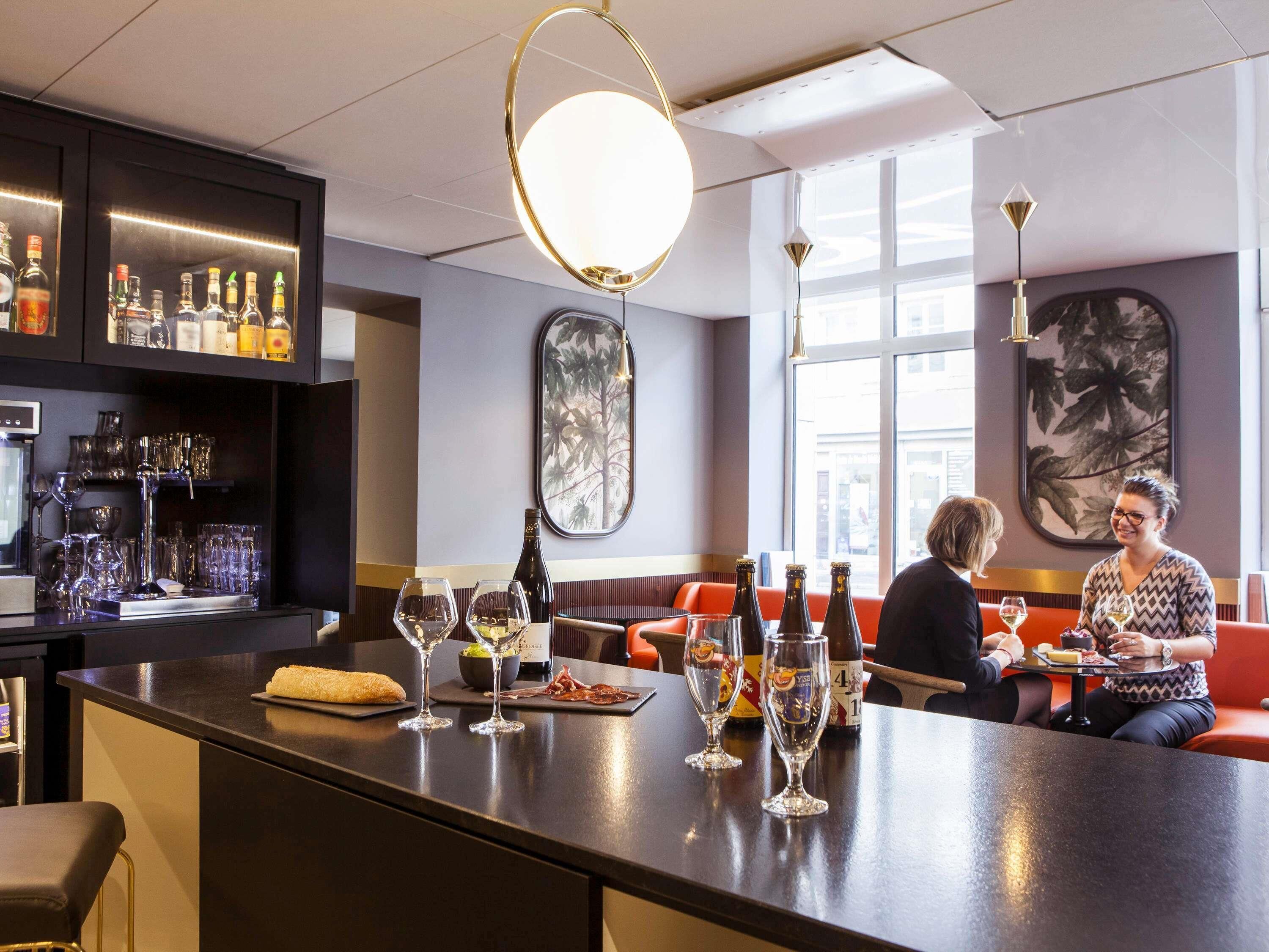 A bar area with a counter, wine glasses, bottles, and seating.