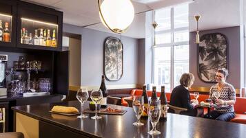 A bar area with a counter, wine glasses, bottles, and seating.