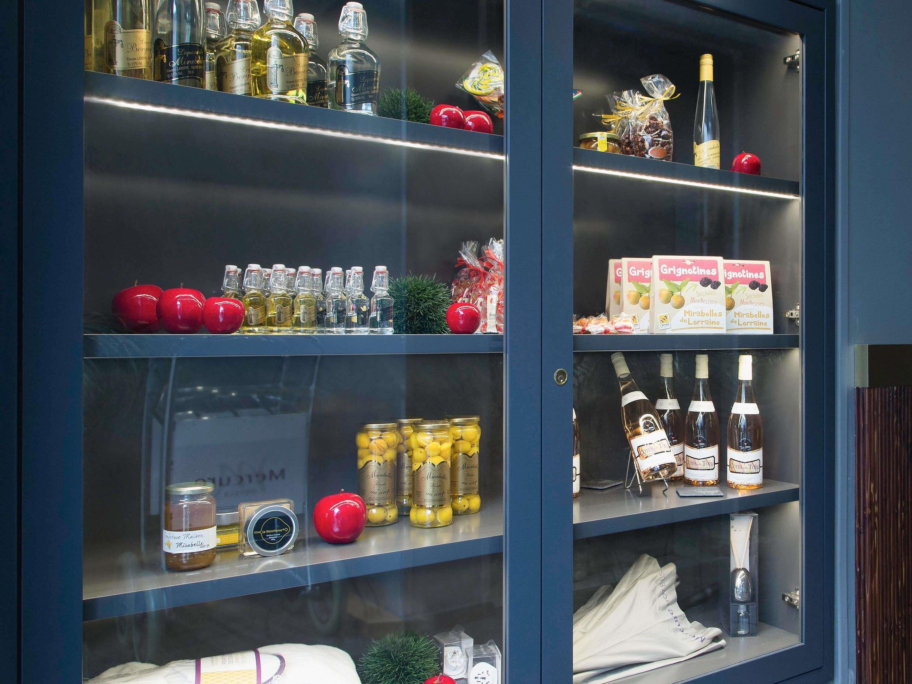 Una vitrina exhibe diversos alimentos y bebidas, como frascos de conservas, botellas de vino y cajas de aperitivos.