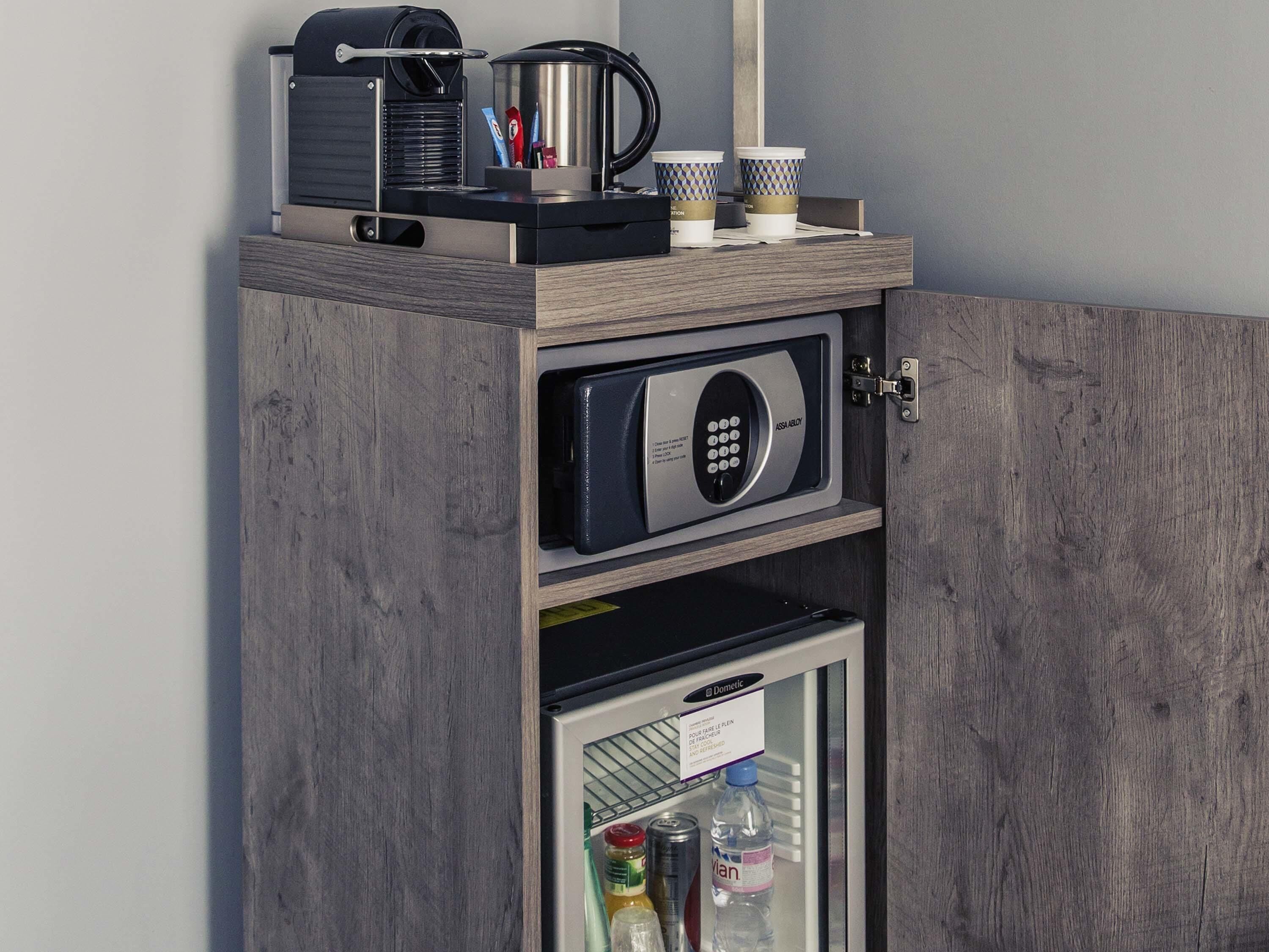 Un minibar con cafetera, tazas y un refrigerador Domesic que contiene bebidas y condimentos.
