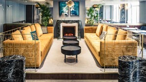 A modern living room with two sofas, a fireplace, and a coffee table. - Mercure Nancy Centre Place Stanislas Hotel (Nancy)