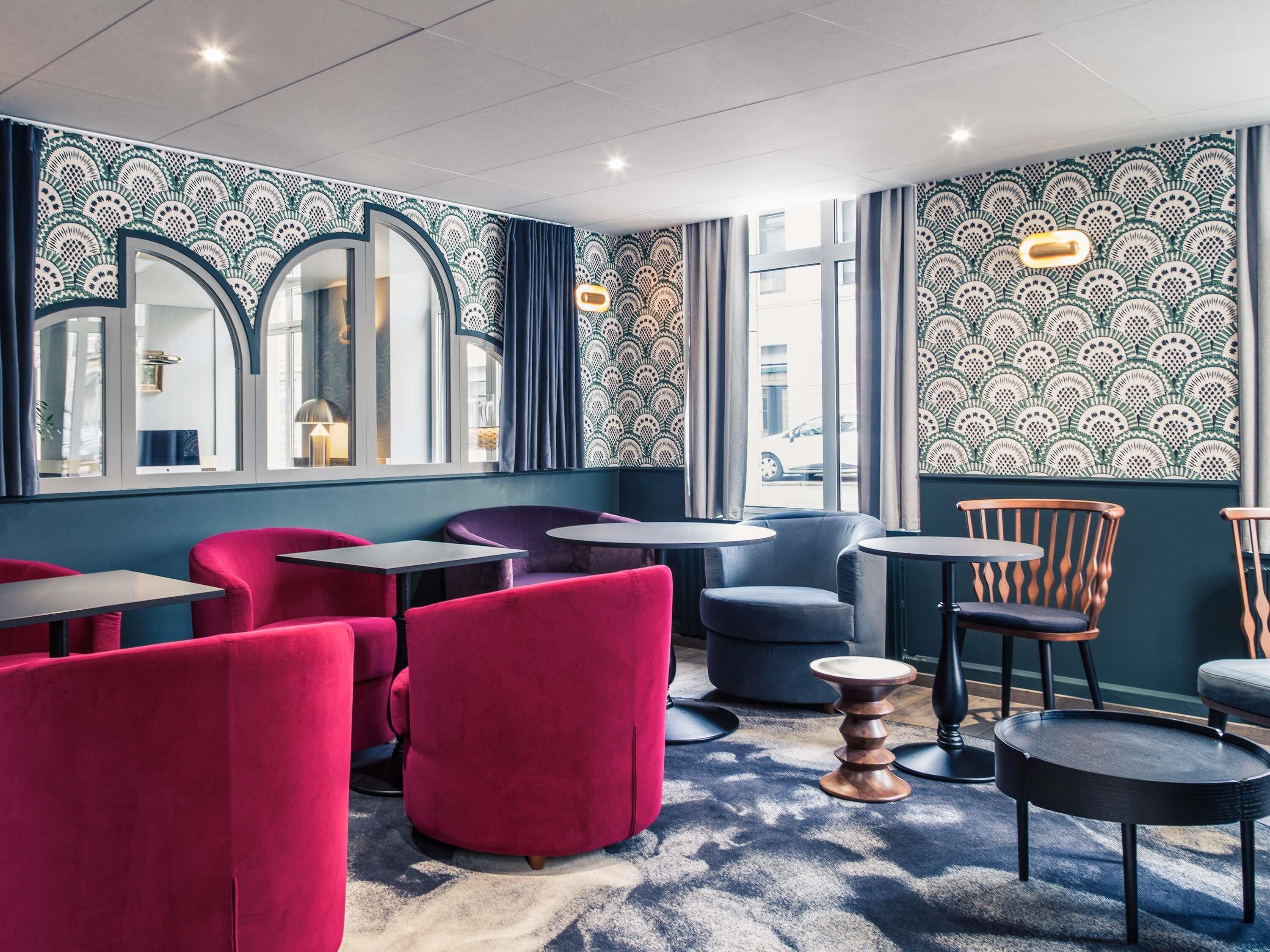 A modern interior with seating arrangements, patterned walls, and large windows.