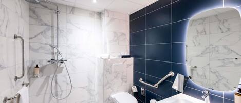 A modern bathroom with a shower, toilet, sink, and a large mirror.