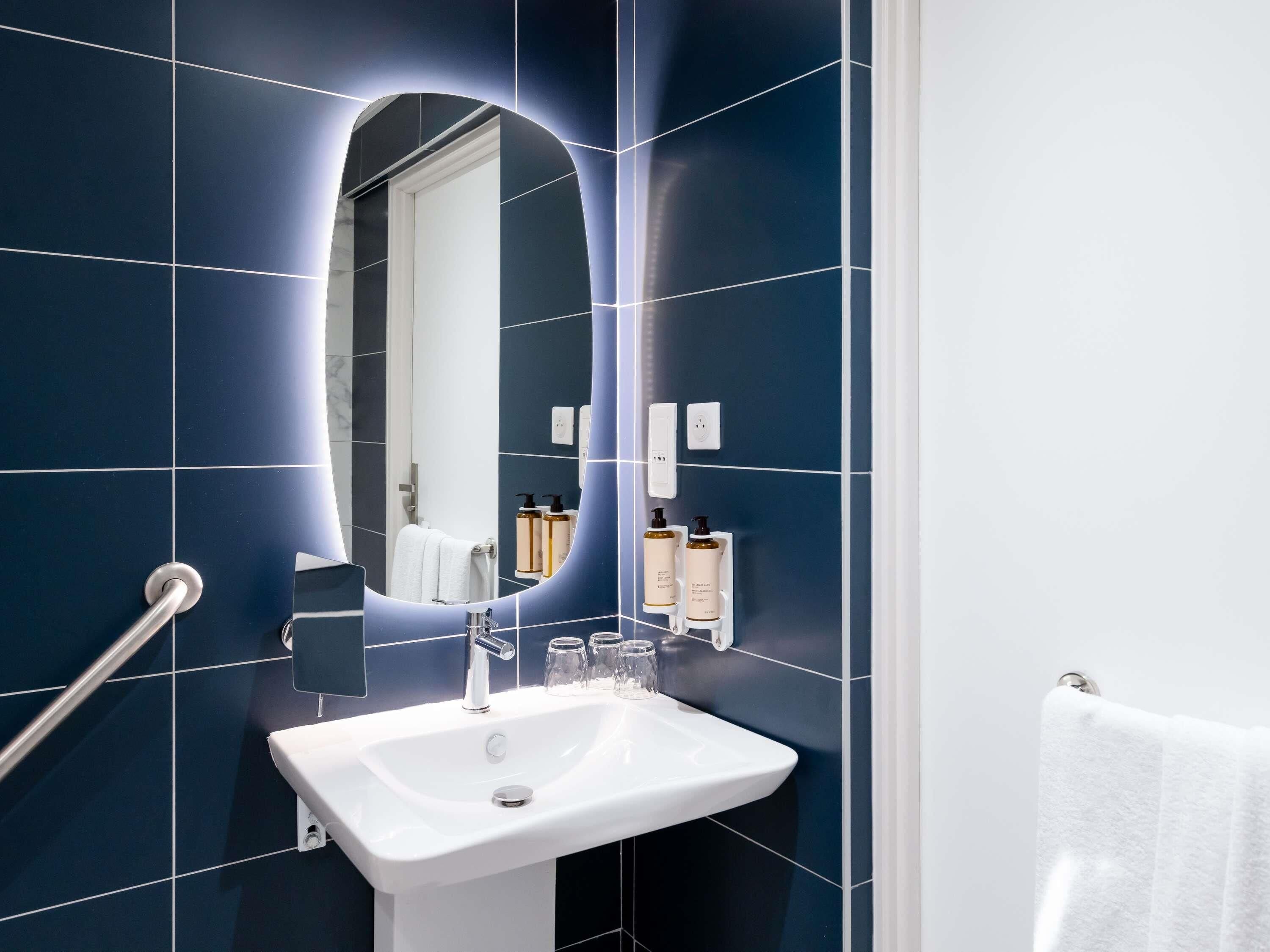 A bathroom with a white sink, a mirror, and a towel rack.
