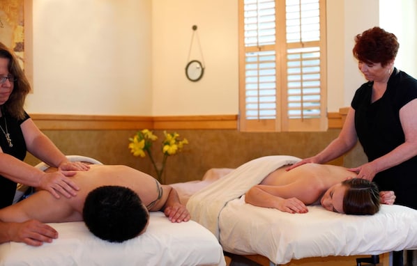 Un cuarto de masoterapia con dos clientes recibiendo masajes en la espalda.