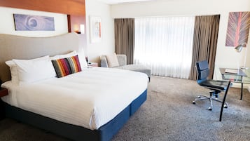 A hotel room with a large bed, a desk, and a chair.
