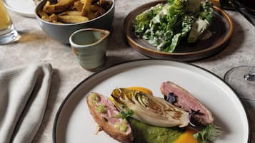 A dining table with plates of food, including a steak, a green vegetable, and a salad.