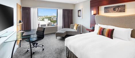 Een hotelkamer met een bed, een bureau, een stoel, een klein tafeltje en een televisie.