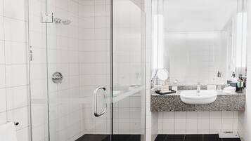 A modern bathroom with a glass shower enclosure, a granite countertop sink, and a large mirror.