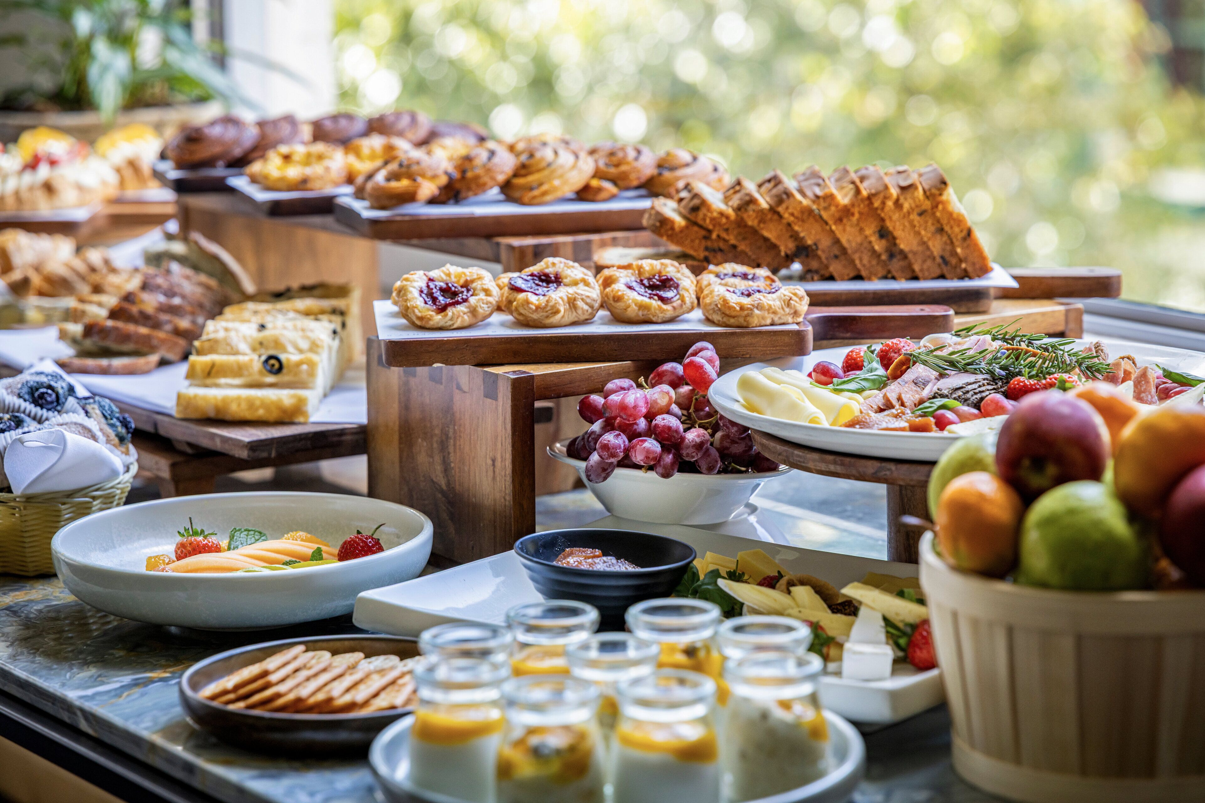 A buffet with various food items and a bowl of fruits.