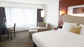 Una habitación de hotel con una cama grande, un escritorio, una silla y una lámpara.