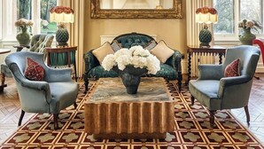 A room with a large ornate mirror, a tufted sofa, two armchairs, a patterned rug, and a chandelier. - Brownsover Hall Hotel  (Rugby)