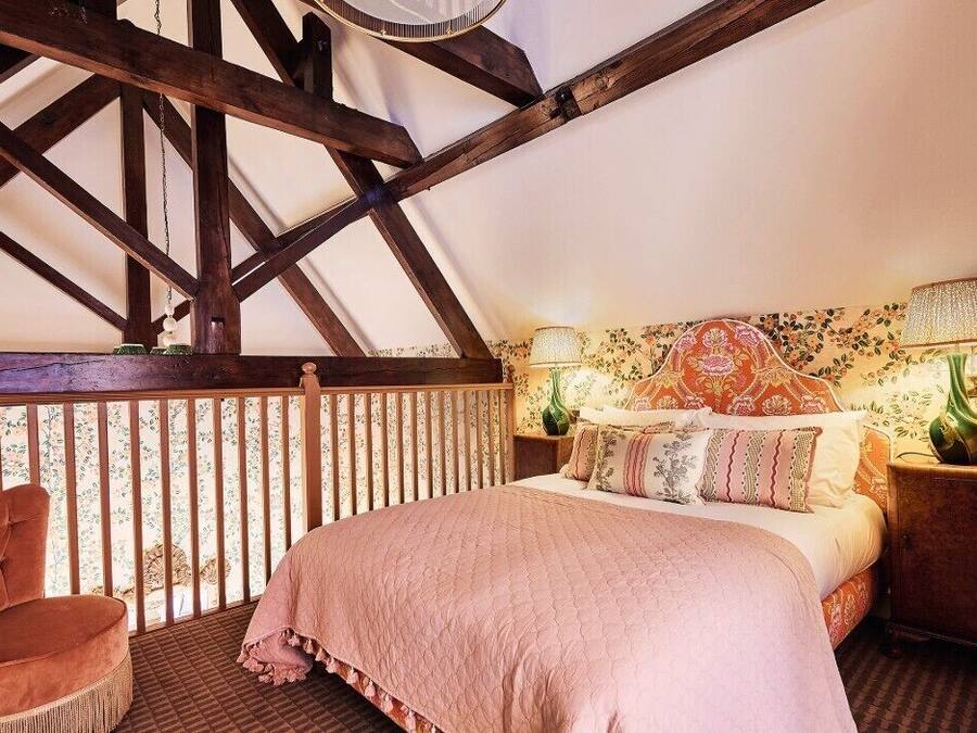 A bedroom with a bed, a chair, a nightstand, and a lamp.