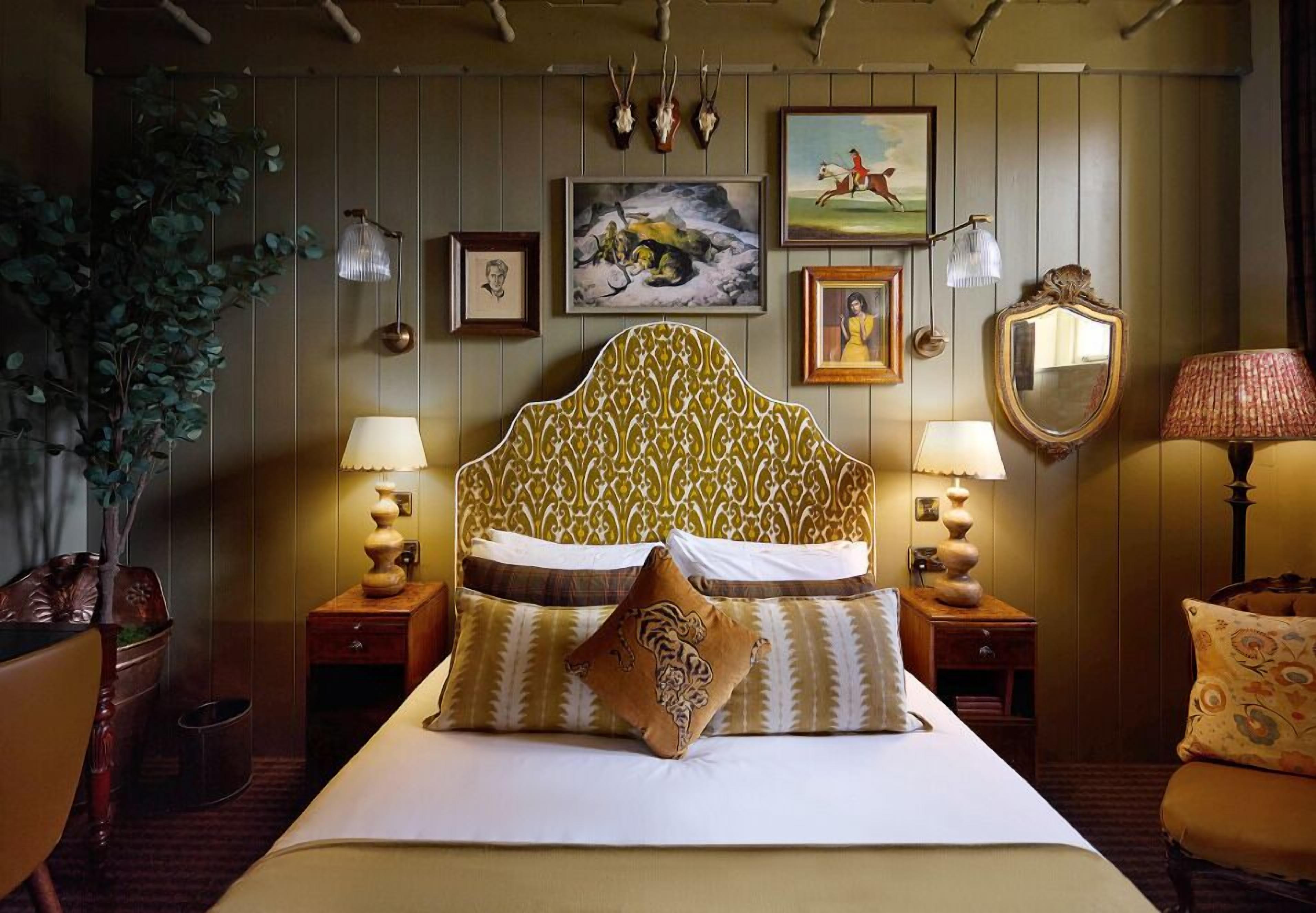 A bed with a patterned headboard, bedside lamps, and framed artwork on the wall.