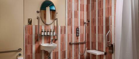Et badeværelse med toilet, vask, spejl, bruser og flisebeklædte vægge.