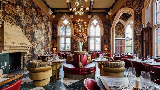 A restaurant with round tables, red chairs, and a fireplace. - Brownsover Hall Hotel  (Rugby)