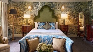 A bedroom with a large bed, two bedside tables, a nightstand, a mirror, a chair, and a carpeted floor. - Brownsover Hall Hotel  (Rugby)